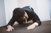 土下座をしながら次の予定に遅れないよう時計を気にするビジネスパーソン